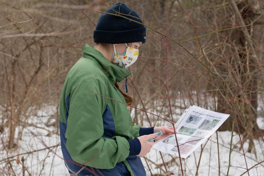 一个学生站在外面的雪地里查看正规澳门赌场网络鸟类的传单