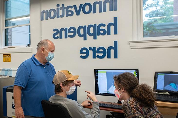 Two students get help from a mentor while working on an innovation project