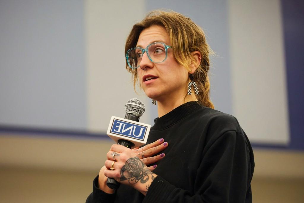 A woman speaks into a U N E-branded microphone at a President's Forum event