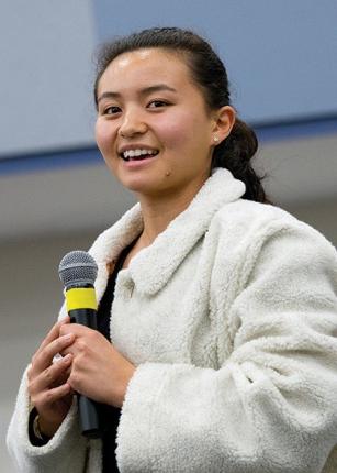 A student speaks into a microphone at a President's Forum