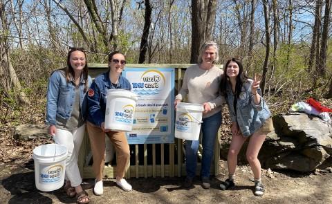 学生 and a UNE staff member gather in front of the Clean Seas UNE beach cleanup kiosk at Freddy Beach